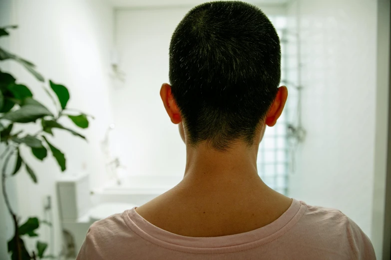 a man in a pink shirt standing in a bathroom, a tattoo, inspired by Zhang Kechun, unsplash, back of head, cybernetic neck implant, with short hair, in kaethe butcher