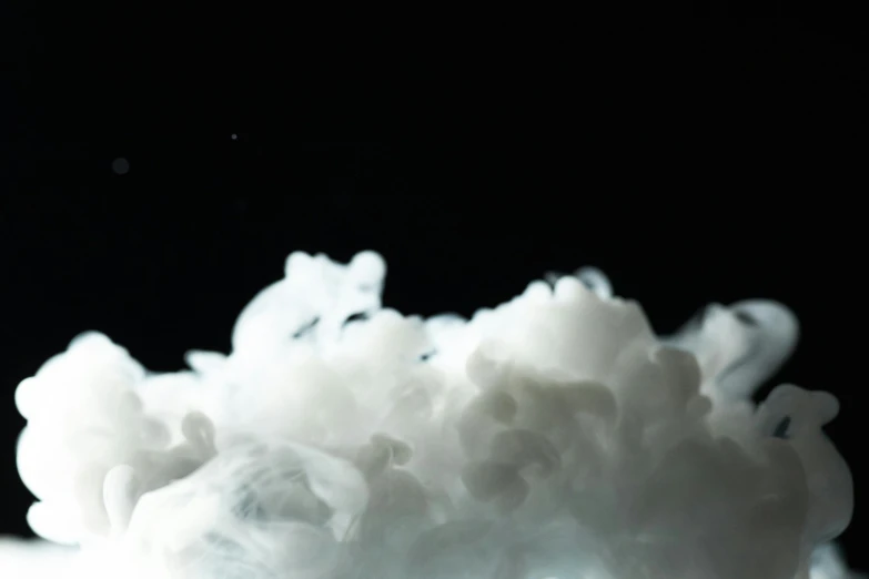 a close up of a white substance on a table, inspired by Kim Keever, unsplash, puffy cute clouds, with a black background, white foam, shot with canon 5 d mark ii