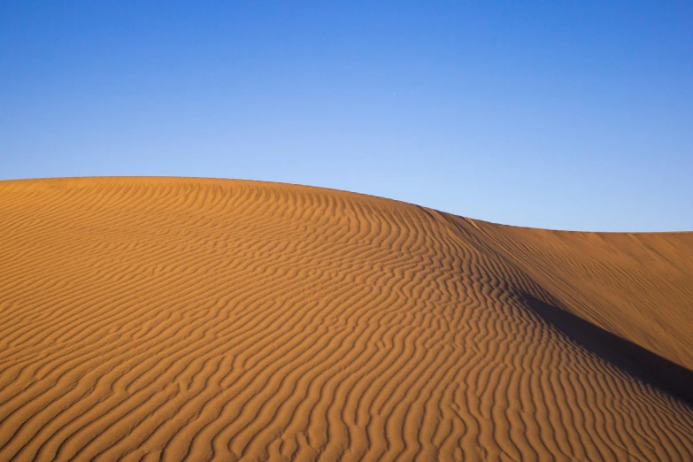 a large sand dune in the middle of a desert, by Peter Churcher, fan favorite, cloudless sky, ripples, medium-shot