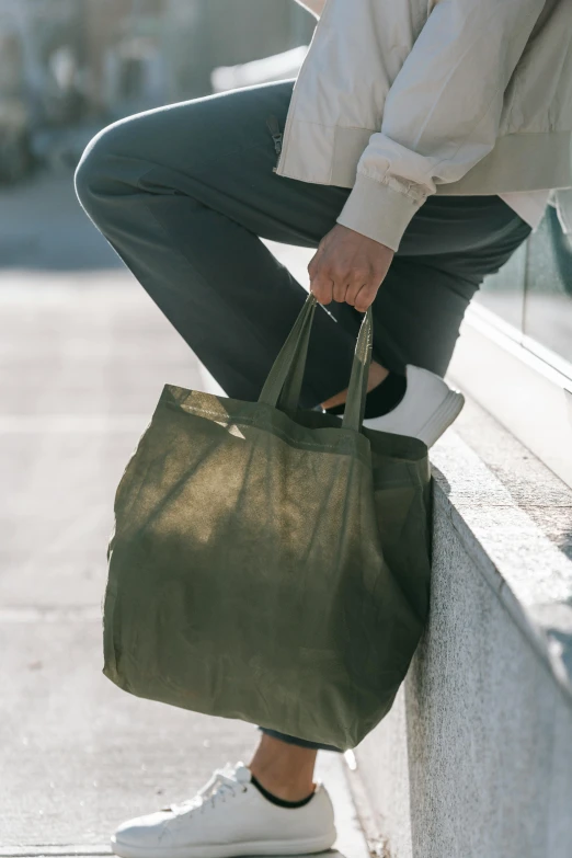 a person sitting on a ledge with a bag, olive green, thumbnail, corduroy, exiting store