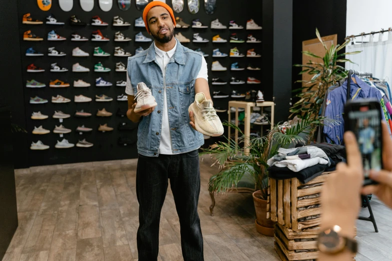 a man standing in a shoe store holding a pair of shoes, pexels contest winner, rapper, with full descriptions, light skin, drew hill