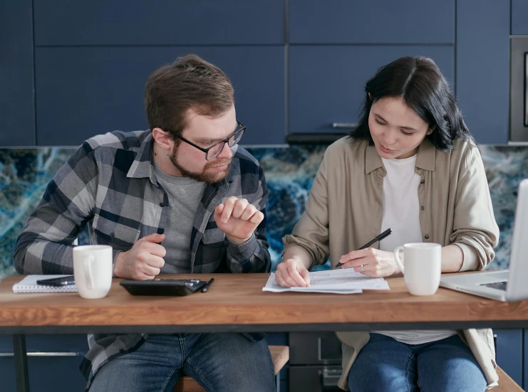 a man and a woman sitting at a kitchen table, pen and paper, aussie baristas, supportive, college