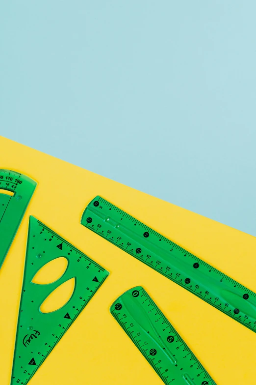 a pair of green rulers sitting on top of a yellow piece of paper, by Julia Pishtar, geometry, banner, on high-quality paper, 8