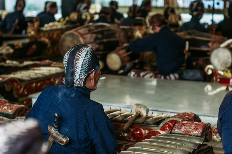 a group of people playing musical instruments in a room, a silk screen, pexels contest winner, hurufiyya, bali, on a wooden tray, thumbnail, back