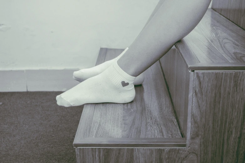 a close up of a person's legs on a step, aestheticism, small heart - shaped face, socks, colorless, indoor picture