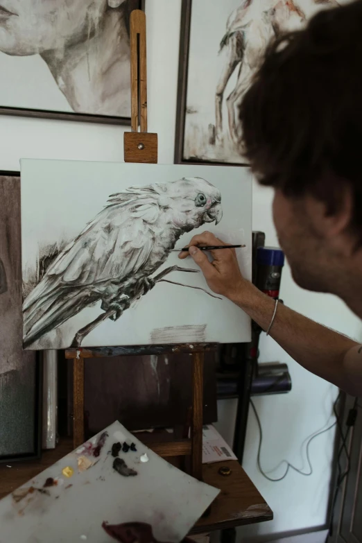 a man that is standing in front of a painting, a detailed painting, inspired by Patrick Pietropoli, process art, tawny frogmouth, detailed 4 k drawing, in a studio, made in tones of white and grey
