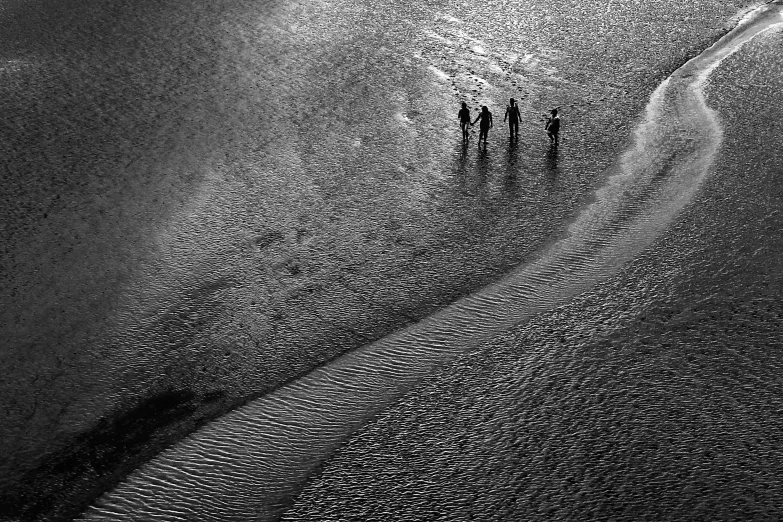 a group of people standing on top of a sandy beach, a black and white photo, by Sudip Roy, unsplash contest winner, minimalism, crossing the river, drone photograpghy, contre jour, ffffound