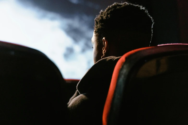 a man sitting in front of a screen watching a movie, pexels contest winner, black teenage boy, over the shoulder view, quality cinema model, [ theatrical ]