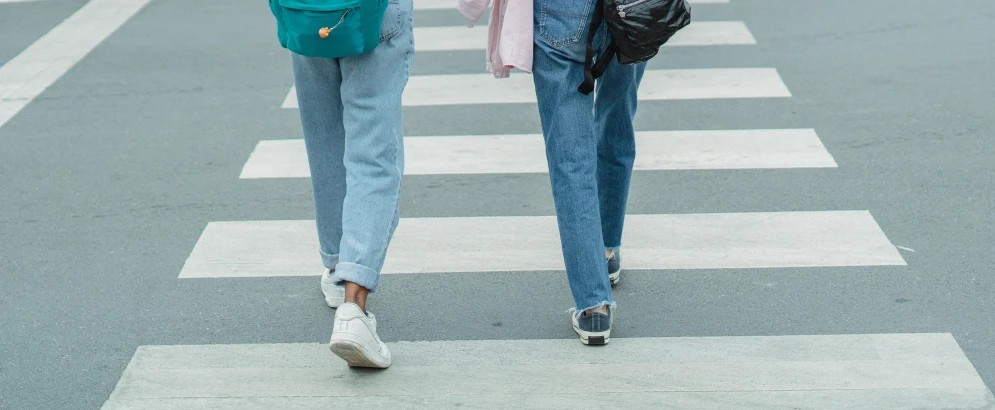 a couple of women walking across a street, trending on pexels, blue jeans, background image, schools, uncropped