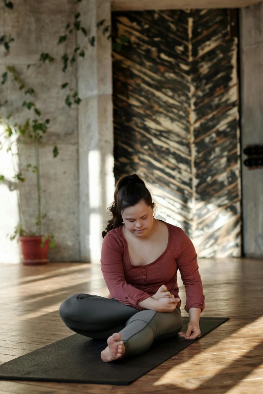 a woman sitting on a yoga mat in a room, downward somber expression, square, squatting, high-quality photo
