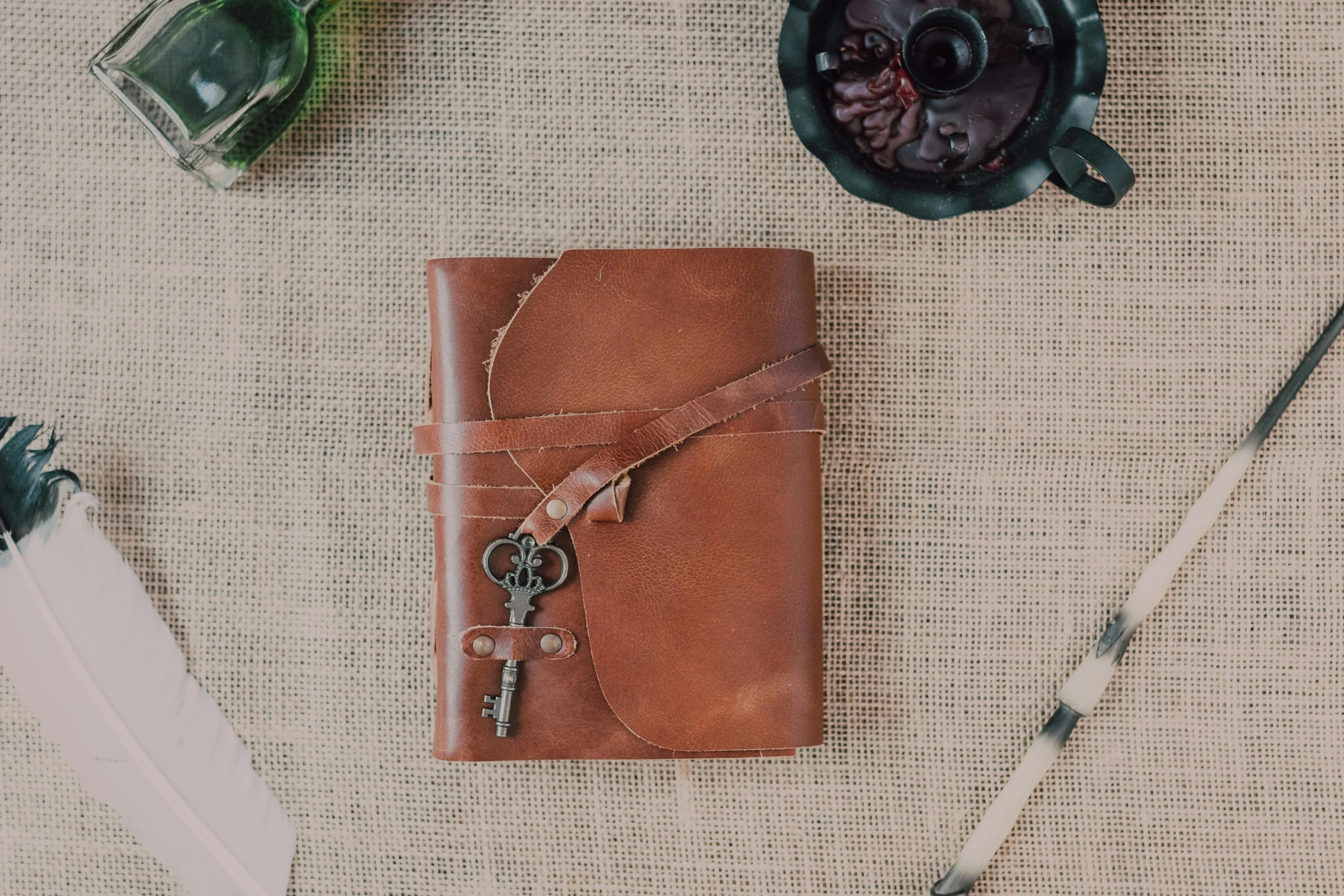 a leather journal sitting on top of a table, inspired by Leonardo da Vinci, unsplash, potion belt, the key of life, front portrait, tan