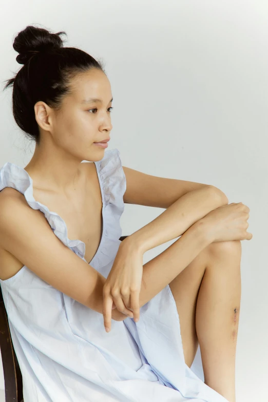 a woman sitting on top of a wooden chair, inspired by Fei Danxu, pexels, renaissance, wearing a light blue shirt, clean face and body skin, nightgown, wearing a tank top and shorts