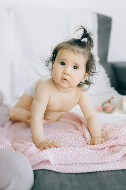 a baby laying on a pink blanket on a bed, pexels contest winner, walking towards camera, looking her shoulder, ad image, hair