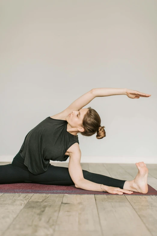 a woman doing a yoga pose on the floor, by Rachel Reckitt, unsplash, arabesque, studio photo, arms to side, long tail, half image