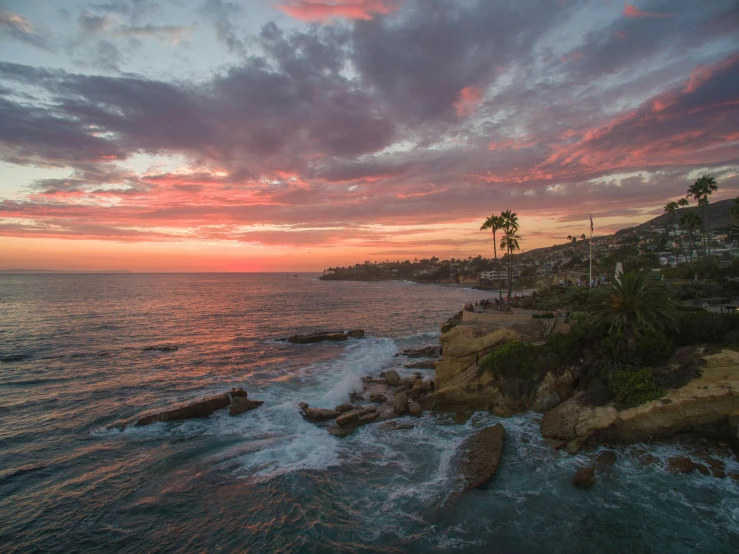 a sunset over the ocean with palm trees in the foreground, by Josh Bayer, pexels contest winner, cliffside town, pink, peter hurley, martin sandiego