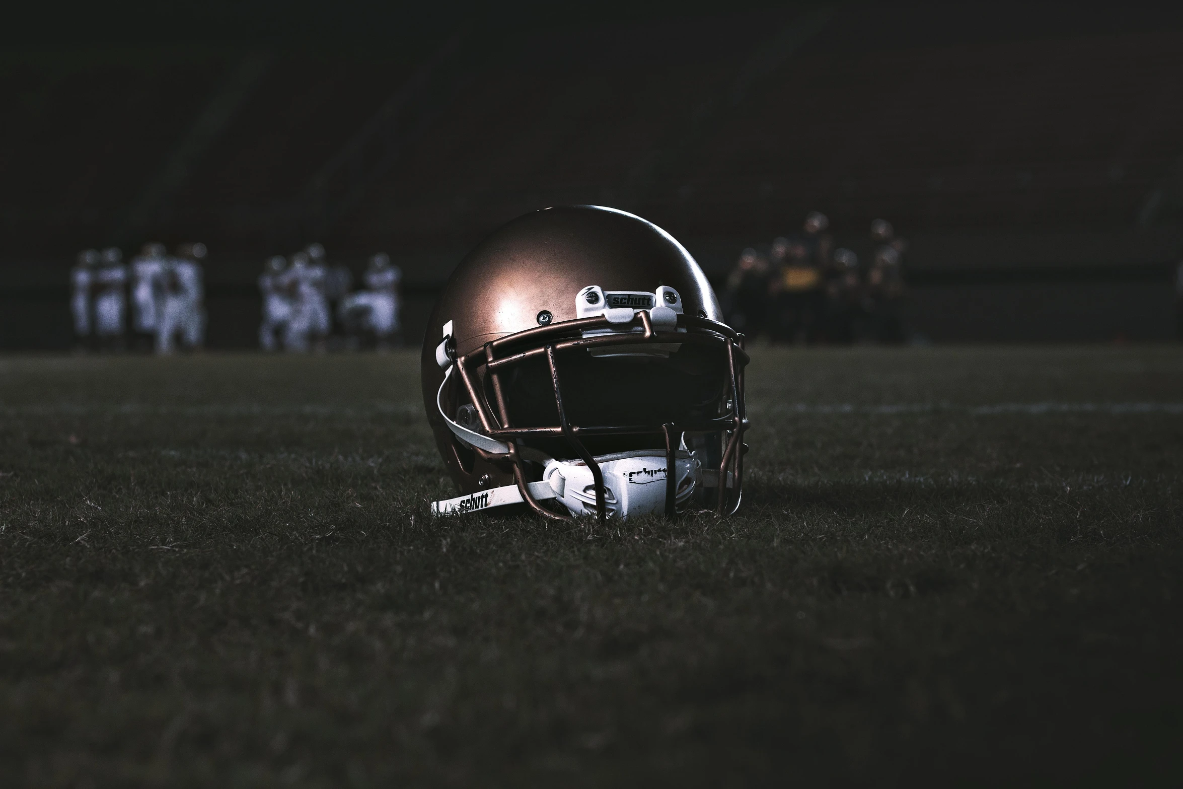 a football helmet sitting on top of a field, by Daniel Lieske, pexels contest winner, dark and beige atmosphere, golden and copper shining armor, instagram picture, (night)