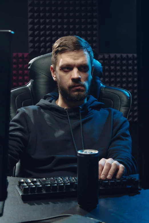 a man sitting at a desk in front of a computer, gaming chair, dark backround, wearing a track suit, ryan dening