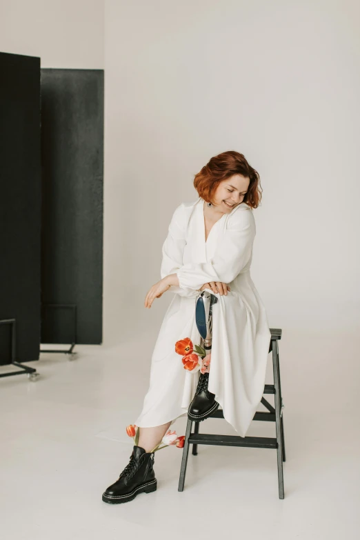 a woman sitting on a chair in front of a television, an album cover, by Anita Malfatti, pexels contest winner, renaissance, white robe, plus size woman, redhead woman, white studio background