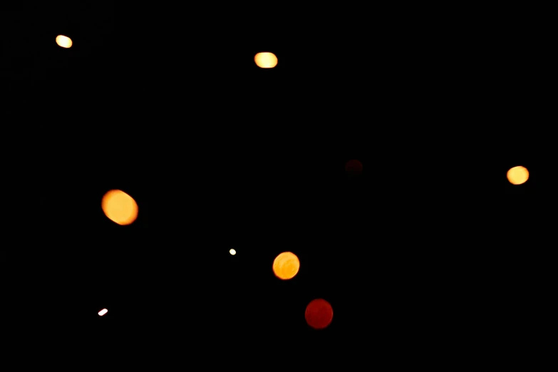 a bunch of lights that are in the dark, an album cover, light and space, scattered gold coins, (light orange mist), low quality grainy, drone camera lens orbs