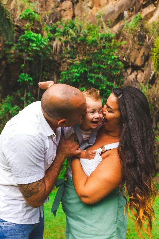 a man standing next to a woman and a baby, pexels contest winner, in a tropical forest, loving embrace, maori, husband wife and son