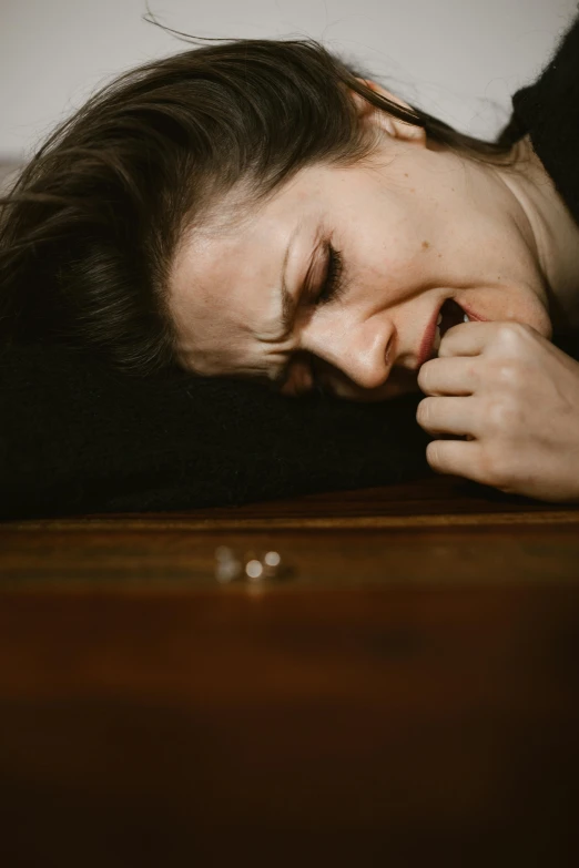 a woman laying on top of a wooden table, by Elsa Bleda, pexels, renaissance, tears running down face, coughing, overdose, profile image