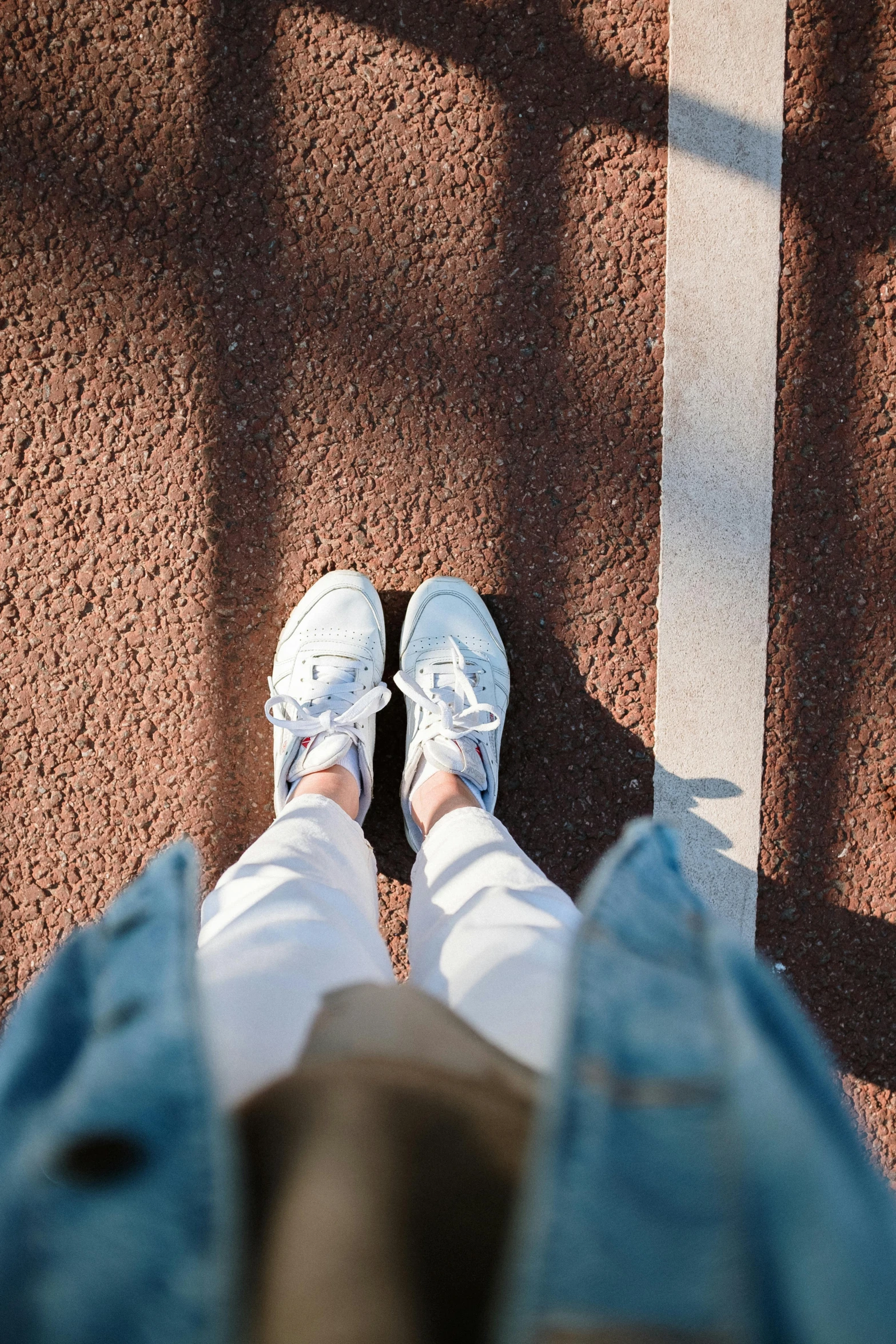 a person standing on top of a tennis court, a picture, pexels contest winner, wearing white sneakers, bright sun bleached ground, looking up at camera, camera looking up at her