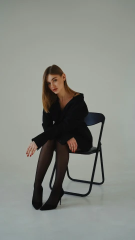 a woman sitting on a chair in a black dress, inspired by Elsa Bleda, pexels contest winner, realism, wearing causal black suits, portrait sophie mudd, gif, minimalistic