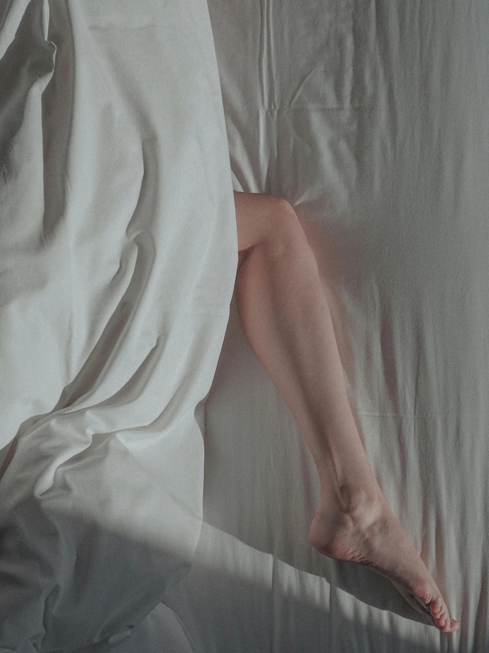 a woman laying on top of a bed covered in white sheets, pexels contest winner, bare leg, it's getting dark, gif, ilustration