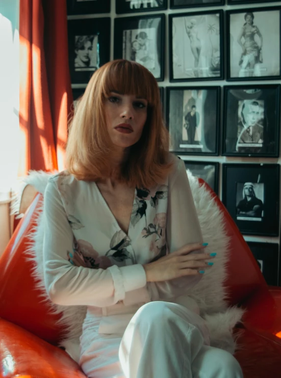 a woman sitting on top of a red couch, an album cover, inspired by Elsa Bleda, pexels contest winner, ginger hair, straight bangs, wearing silver silk robe, **cinematic