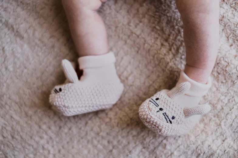 a close up of a baby wearing a pair of shoes, by Nina Hamnett, pexels, rabbit face only, crochet skin, textured base ; product photos, bath