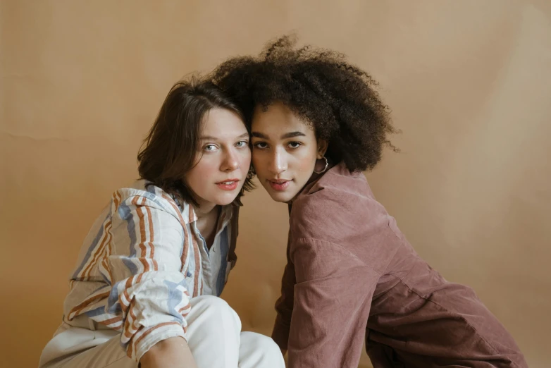 a couple of women sitting next to each other, trending on pexels, renaissance, brown curly hair, neutral pose, brown:-2, brown