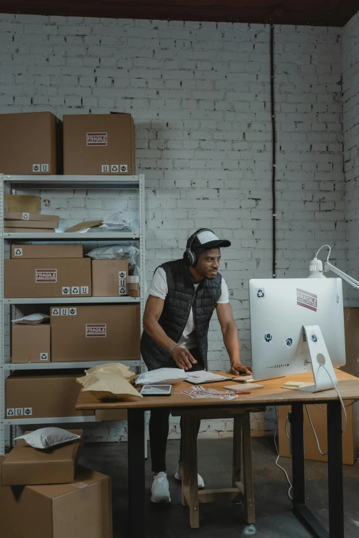 a man sitting at a desk working on a computer, pexels contest winner, delivering packages for amazon, afro tech, in a workshop, avatar image