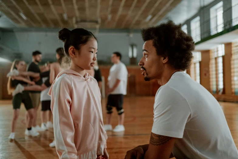 a man sitting next to a little girl on a basketball court, pexels contest winner, antipodeans, 8 0 s asian neon movie still, standing in class, mixed race, reaching out to each other