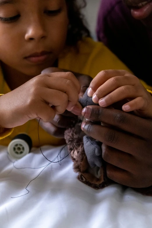 a little girl sitting on top of a bed holding a stuffed animal, by artist, unsplash, process art, sri lanka, aerial view. hand stitching, surgery, clothes made out of veins