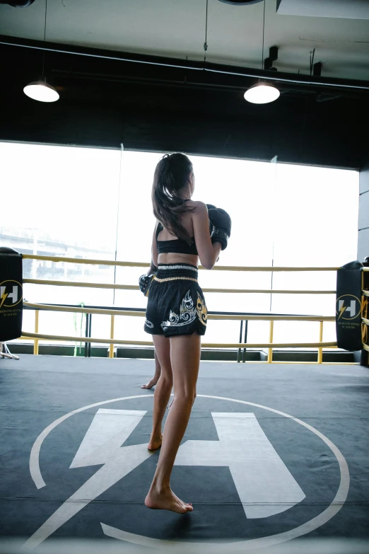 a woman standing in the middle of a boxing ring, bangkok, round thighs, facing away, instagram picture