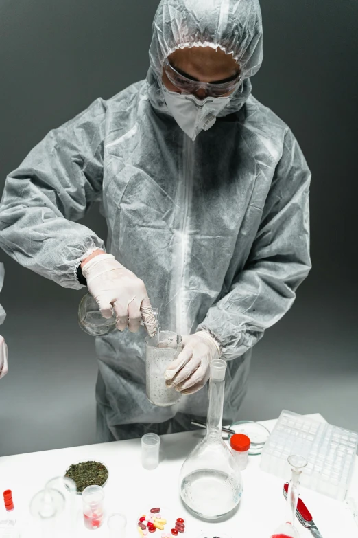 a couple of people that are standing in front of a table, shutterstock, plasticien, flight suit and gloves, pouring, grey, biological photo