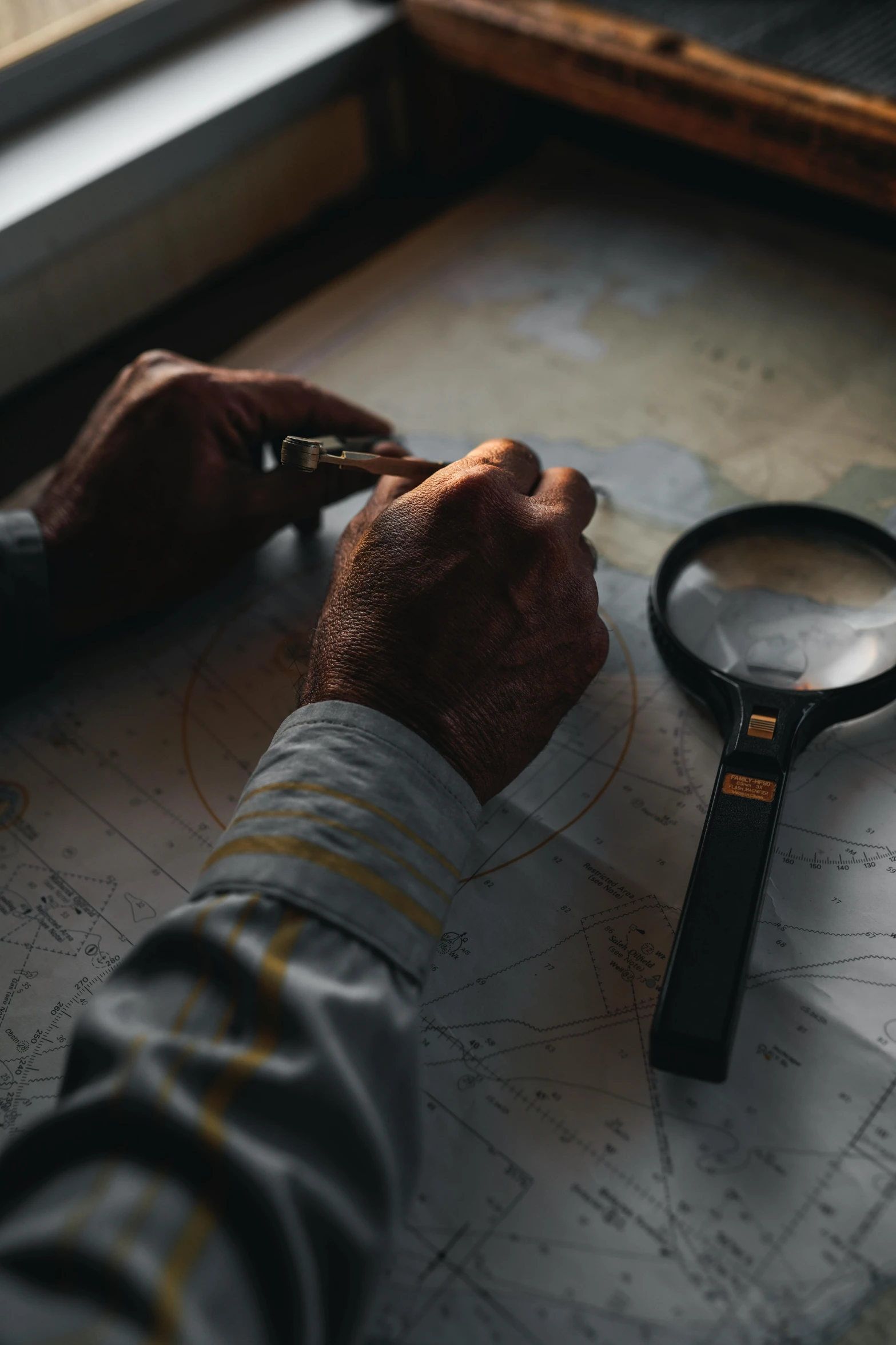 a person looking at a map with a magnifying glass, pexels, looking at us from a porthole, hand on table, crosshatch, inspect in inventory image