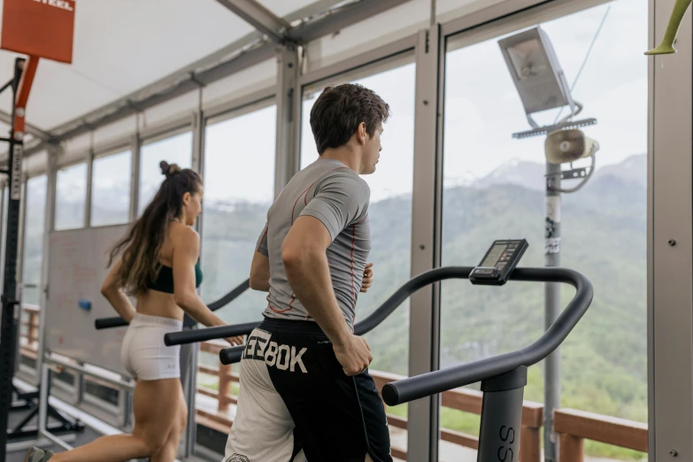 a man and a woman running on a treadmill, a portrait, pexels contest winner, figuration libre, mountains in the background, glass room, herry cavill, view from the side