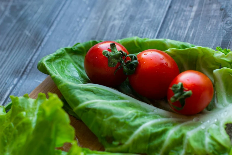 a wooden cutting board topped with lettuce and tomatoes, 6 pack, portrait image, lush greens, full colour