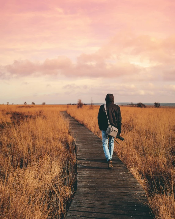 a person walking on a boardwalk in a field, a picture, happening, lgbtq, instagram post, no watermarks, earthy colors