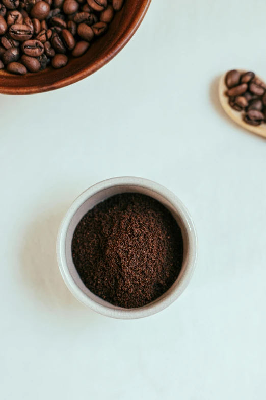 a cup of coffee next to a bowl of coffee beans, by Carey Morris, trending on unsplash, powder, crushed, background image, close-up product photo