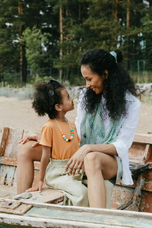 a woman and a child are sitting in a boat, pexels contest winner, symbolism, sitting on a park bench, brown skinned, on wooden table, jewelry