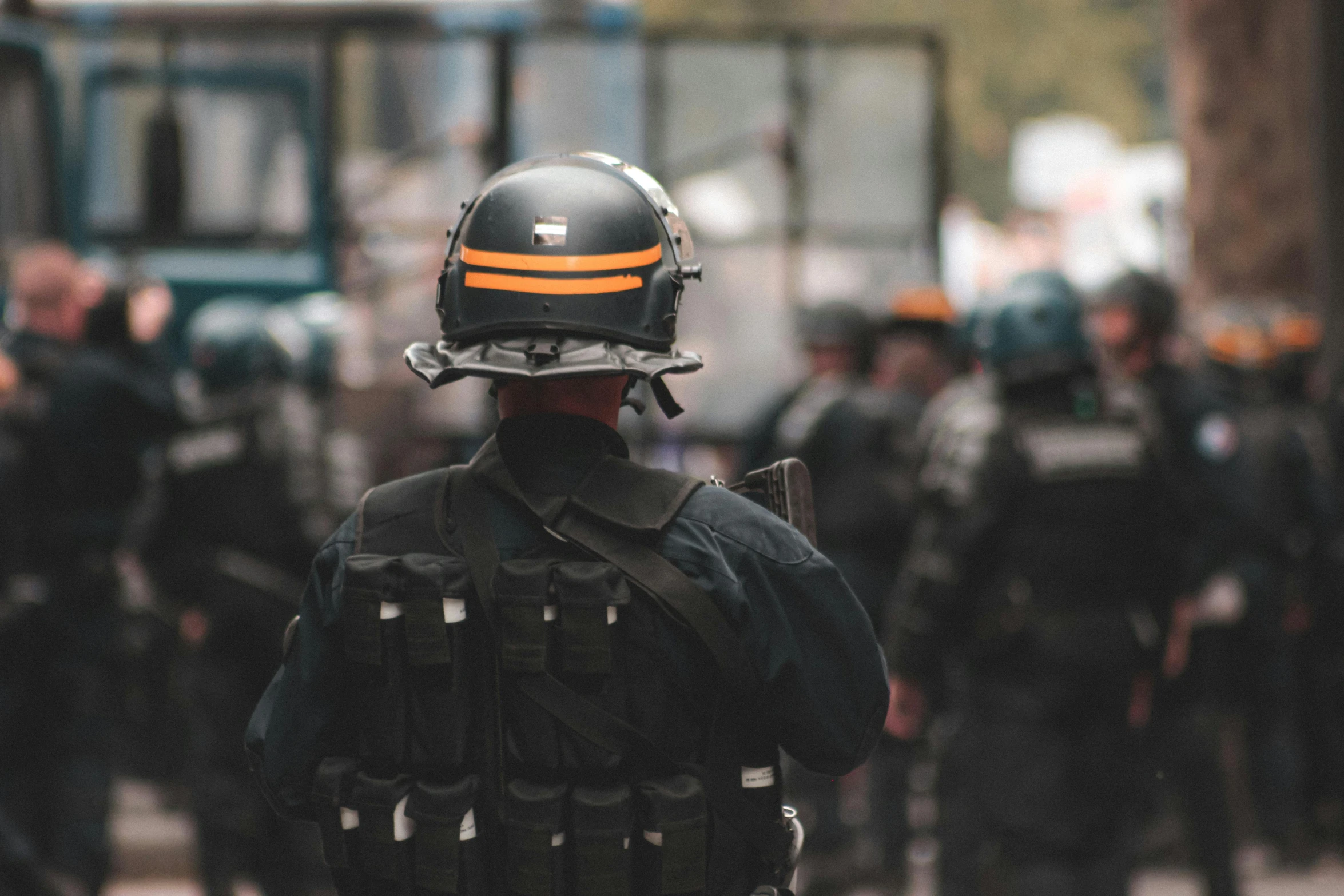 a group of police officers standing next to each other, by Adam Marczyński, pexels, figuration libre, wearing tactical gear, 🚿🗝📝, over his shoulder, riot background