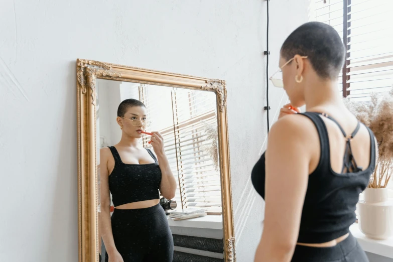 a woman standing in front of a mirror brushing her teeth, by Emma Andijewska, pexels contest winner, pixie cut with shaved side hair, wearing a sexy cropped top, doctors mirror, she is wearing a black dress