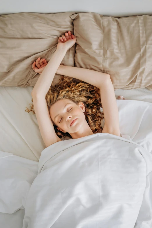 a woman laying in bed with her hands on her head, pexels contest winner, renaissance, curled up under the covers, sydney sweeney, waving arms, high angle view