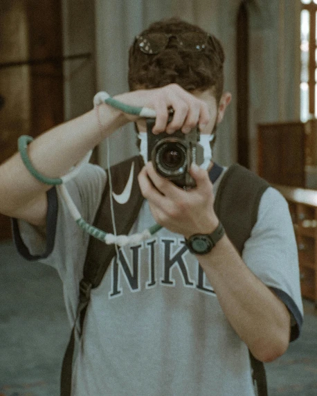 a man taking a picture of himself with a camera, inspired by Elsa Bleda, unsplash contest winner, photorealism, goggles around his neck, at a museum, male teenager, faded color film