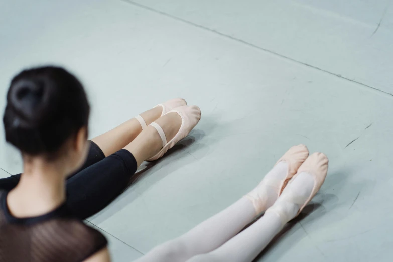 a woman sitting on the floor with her legs crossed, by Elizabeth Polunin, pexels contest winner, arabesque, two skinny figures, standing in class, slippers, rectangle