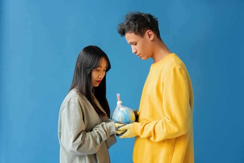a man and a woman standing next to each other, by Adam Marczyński, pexels contest winner, urine collection bag, blue turtleneck, dry ice, asian female