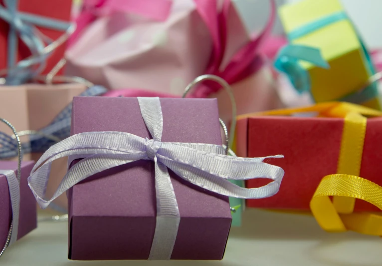 a pile of gift boxes sitting on top of a table, by Eden Box, pexels contest winner, happening, purple ribbons, square, multi colored, small