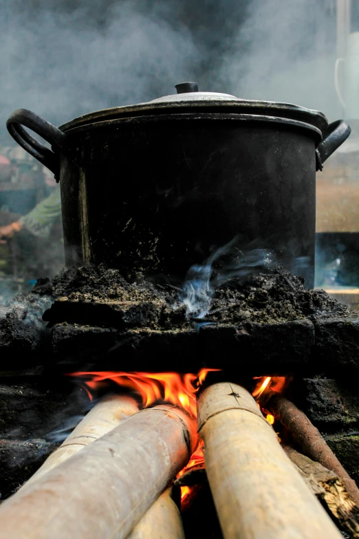 a large pot sitting on top of a fire, food